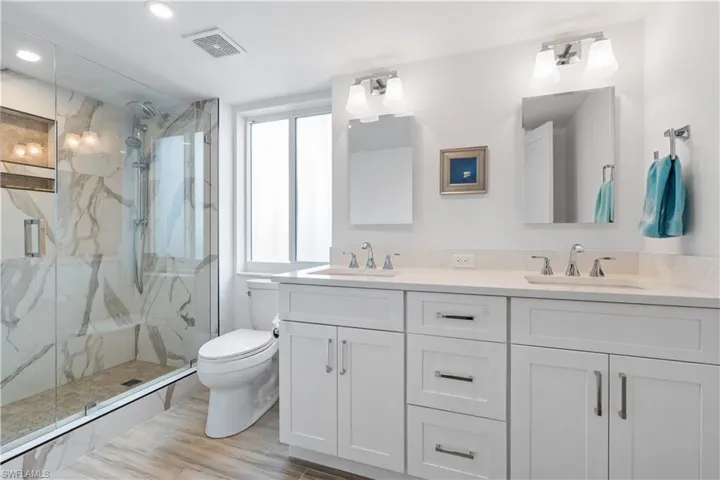 Bathroom featuring hardwood / wood-style floors, vanity, toilet, and a shower with shower door
