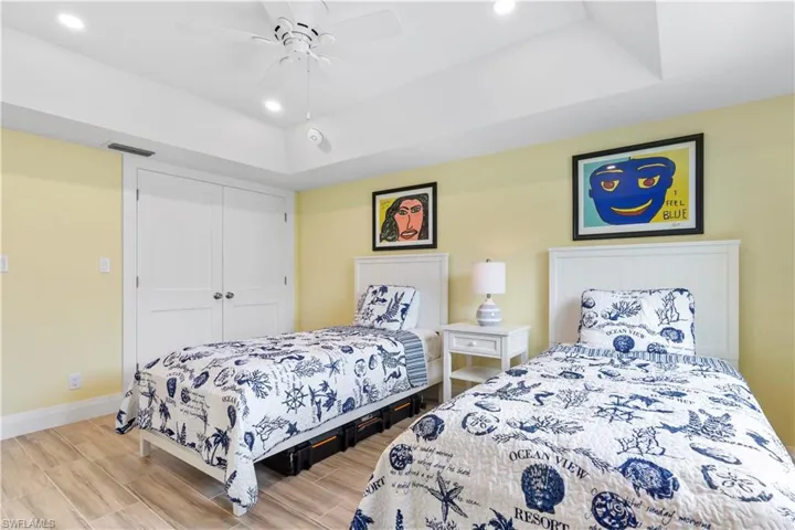 Bedroom featuring light wood-type flooring, ceiling fan, a raised ceiling, and a closet