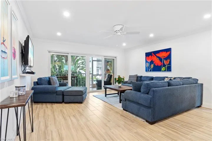Living room with ceiling fan, light wood-type flooring, and ornamental molding