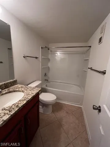Full bath with vanity, shower / washtub combination, and dark tile patterned floors