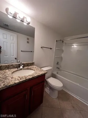 Bathroom with vanity, bathtub / shower combination, and dark tile patterned floors