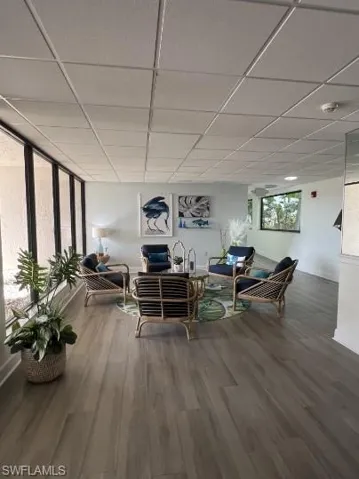 Living area with a paneled ceiling and dark wood-style floors