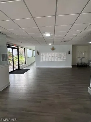 Unfurnished living room with a paneled ceiling and dark wood-style flooring