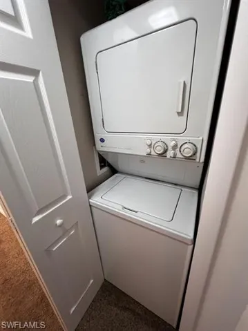 Laundry area with stacked washer / dryer and dark colored carpet