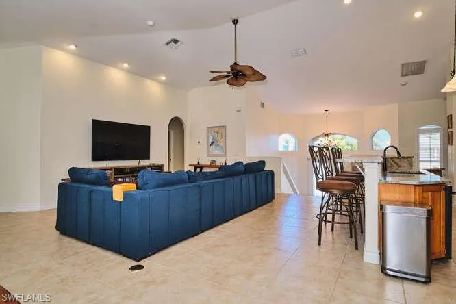 Dining room featuring arched walkways, lofted ceiling, a ceiling fan, and light tile patterned floors