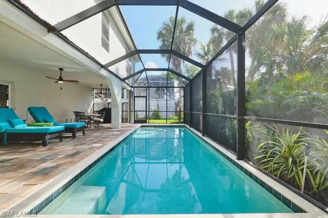 Outdoor pool featuring a patio, a sunroom, and glass enclosure