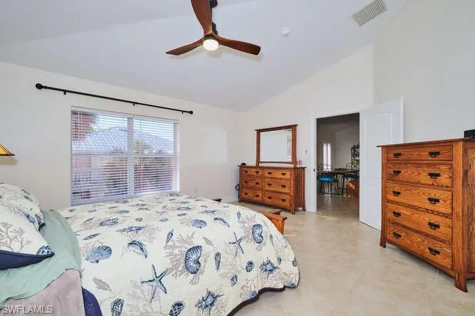 Bedroom with vaulted ceiling, a ceiling fan, and light tile patterned floors