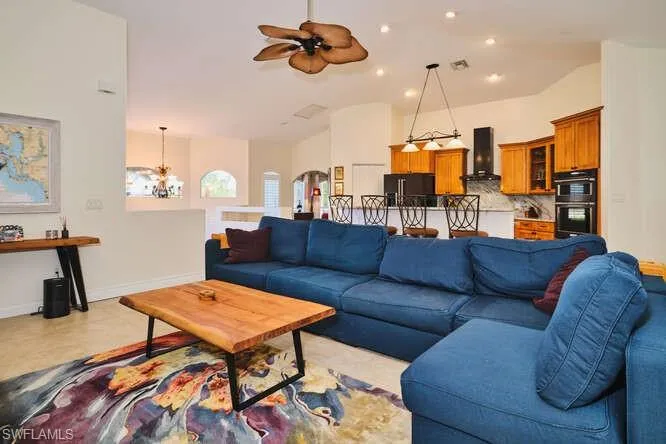 Living area with arched walkways, a chandelier, a ceiling fan, and lofted ceiling