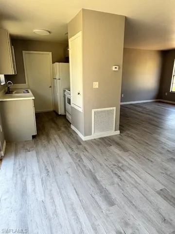 Kitchen with a sink, visible vents, open floor plan, light countertops, and fridge