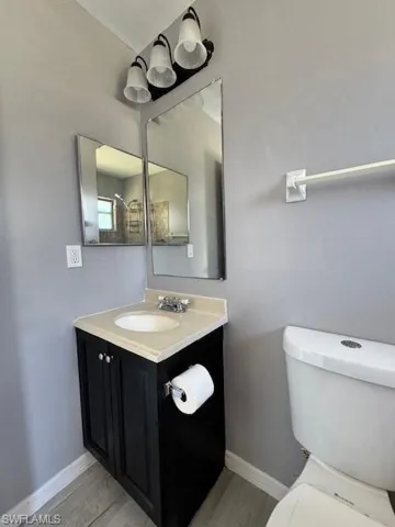 Bathroom with baseboards, vanity, toilet, and wood finished floors