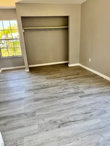 Unfurnished bedroom with a closet, wood finished floors, and baseboards