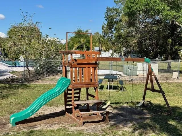 View of playground with a yard and fence