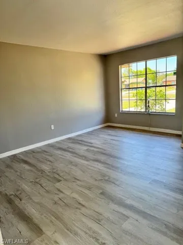 Spare room featuring a textured ceiling, wood finished floors, and baseboards