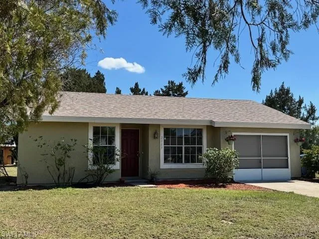 Ranch-style house featuring driveway, stucco siding, a garage, and a front yard