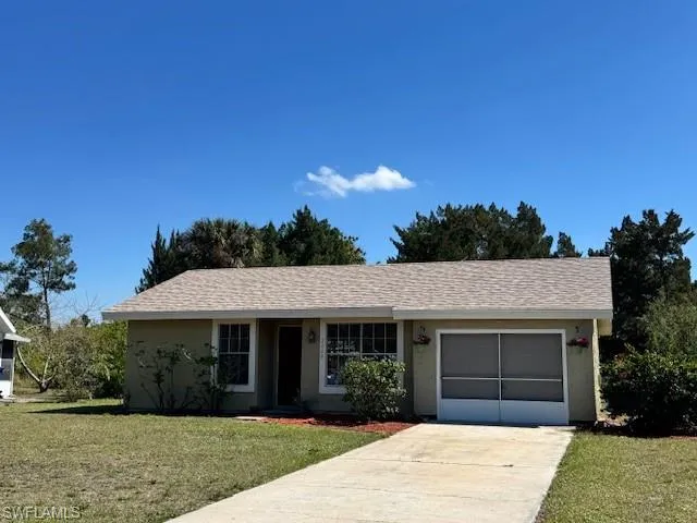 Ranch-style house with a garage, a front yard, concrete driveway, and stucco siding