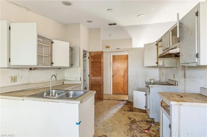 Kitchen with light countertops, open shelves, under cabinet range hood, and white cabinets