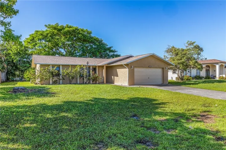 View of front of property featuring driveway, stucco siding, a garage, and a front yard