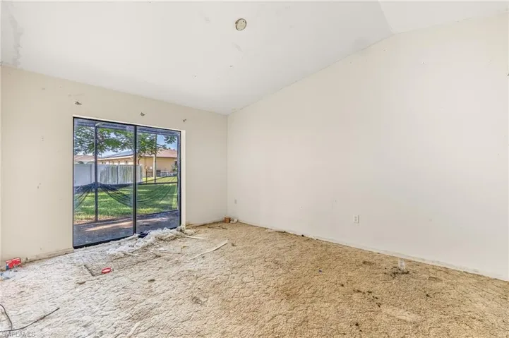 Carpeted spare room featuring vaulted ceiling and baseboards