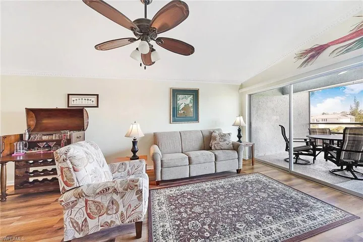 Living area with wood finished floors, ceiling fan, crown molding, and lofted ceiling