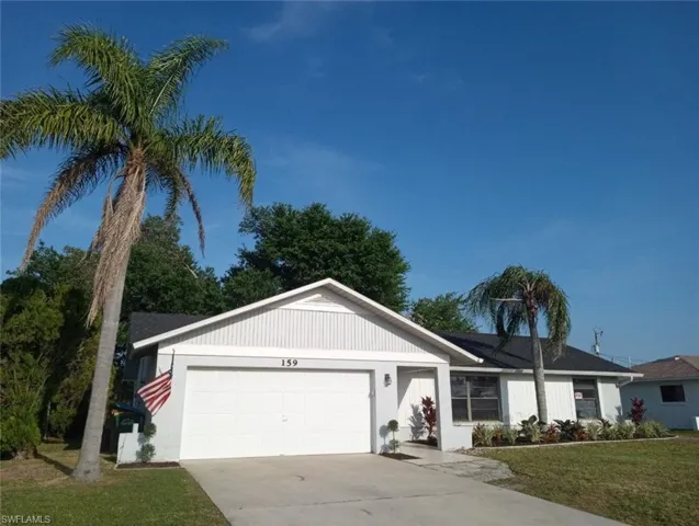 Single-story residence featuring a white garage door, light gray exterior siding, and a black shingle roof