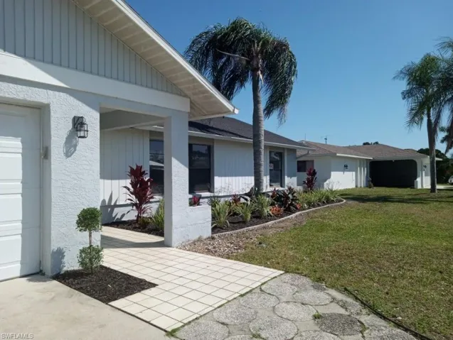 Front exterior showcasing a light-colored stucco finish, a two-car garage, and a covered entry