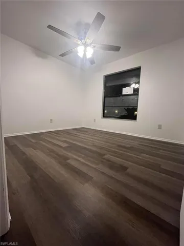 Spacious room featuring wood-finish flooring, a contemporary ceiling fan with integrated lighting, and a window providing natural illumination