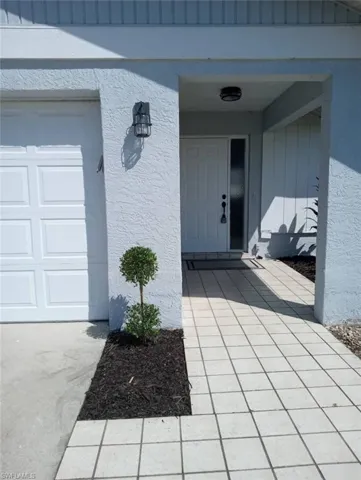 Entryway featuring a paneled door with a sidelight, covered porch, and square tile pathway