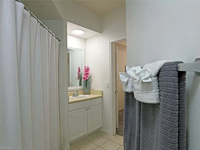 Bathroom with vanity, tile patterned flooring, and a shower with shower curtain