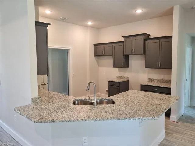 Kitchen featuring kitchen peninsula, sink, light hardwood / wood-style flooring, and light stone counters