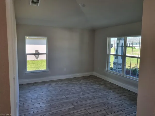Empty room featuring dark hardwood / wood-style flooring and a wealth of natural light