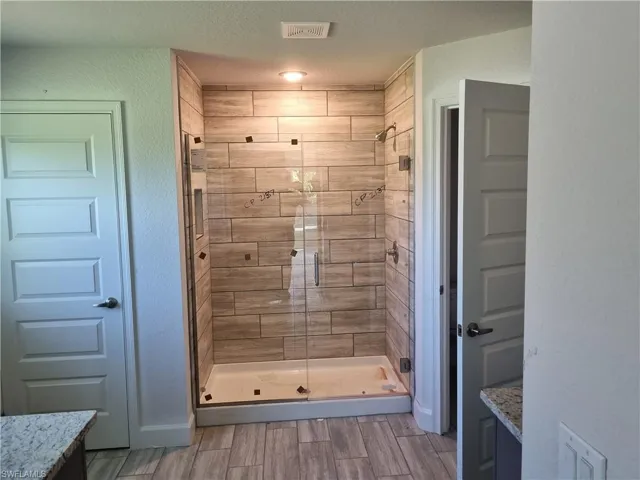 Bathroom featuring vanity, a textured ceiling, and a shower with door