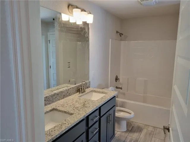 Full bathroom featuring vanity,  shower combination, toilet, and hardwood / wood-style flooring