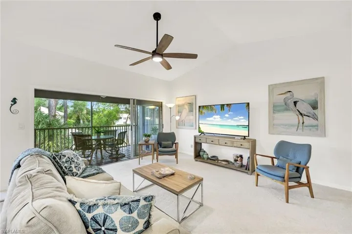 Living area with lofted ceiling, carpet flooring, and a ceiling fan