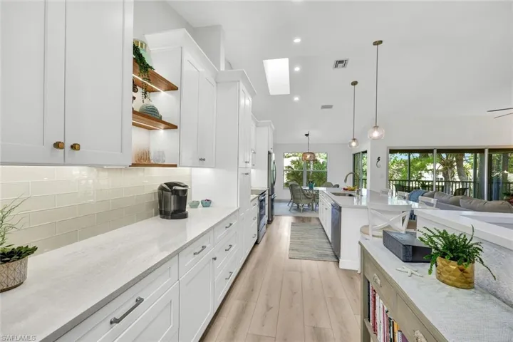 Kitchen with open shelves, white cabinetry, light stone countertops, and decorative light fixtures
