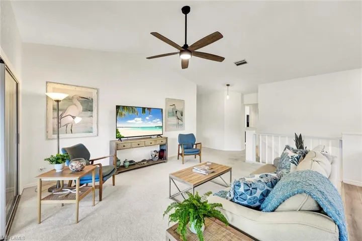 Carpeted living area with lofted ceiling and a ceiling fan