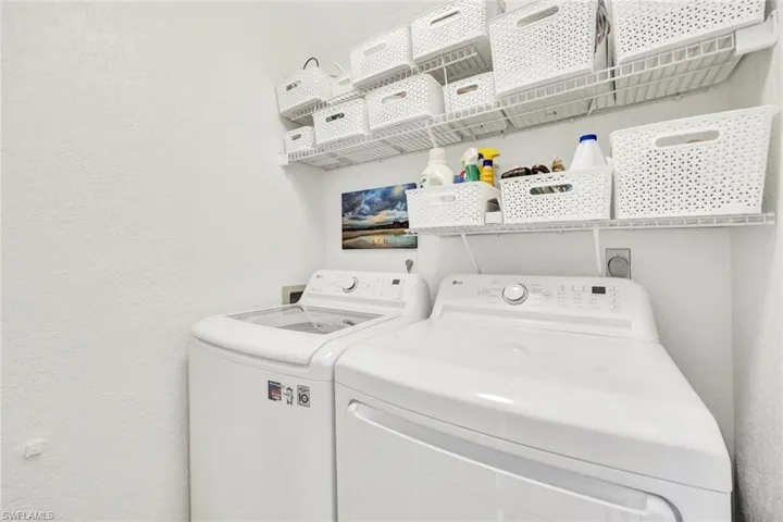 Laundry area featuring a textured wall and washing machine and dryer