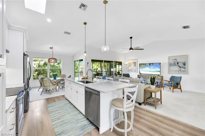 Kitchen featuring white cabinets, a breakfast bar area, stainless steel appliances, light stone counters, and pendant lighting