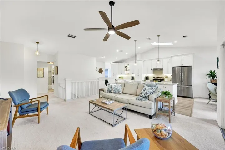 Living area featuring light colored carpet, a ceiling fan, and a high ceiling