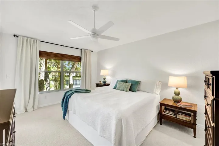 Bedroom with light colored carpet and a ceiling fan