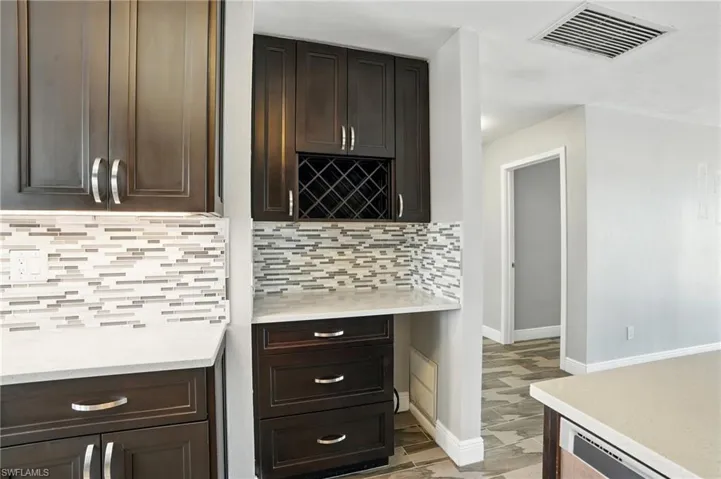 Kitchen featuring light countertops, dark brown cabinets, and decorative backsplash- Virtually Enhanced
