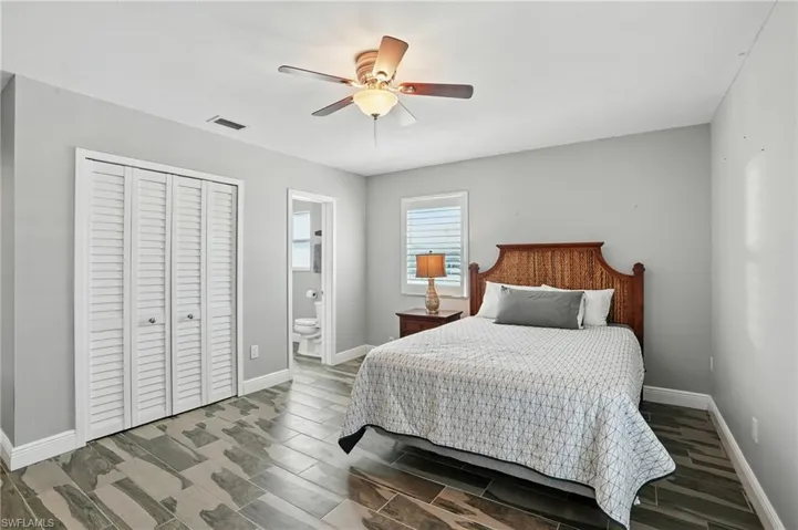 Bedroom with a closet, a ceiling fan, wood tiled floors, and ensuite bathroom- Virtually Enhanced