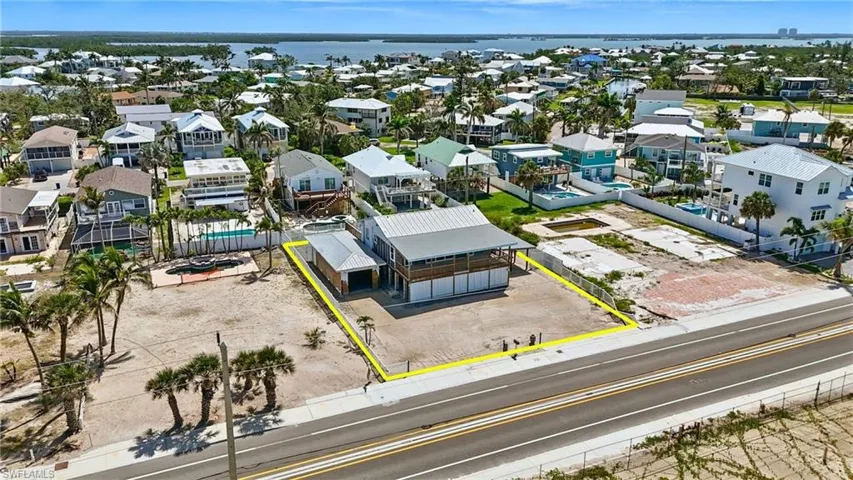 Aerial perspective of suburban area with property parcel outlined and a large body of water- Virtually Enhanced
