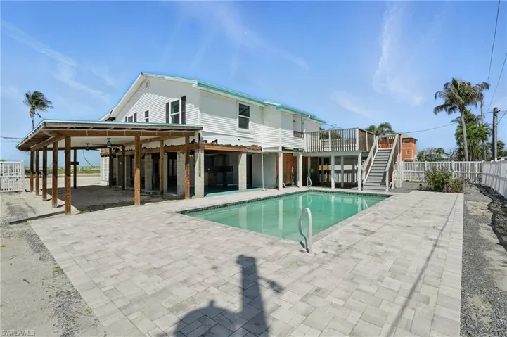 View of swimming pool with stairway, a patio area, a fenced backyard, and a deck- Virtually Enhanced