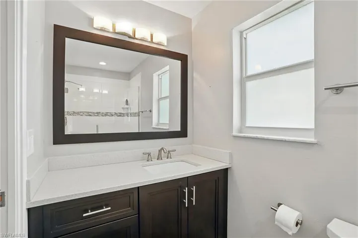 Bathroom featuring vanity, healthy amount of natural light, and tiled shower- Virtually Enhanced