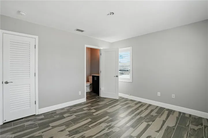 Unfurnished bedroom featuring wood finish floors and connected bathroom- Virtually Enhanced