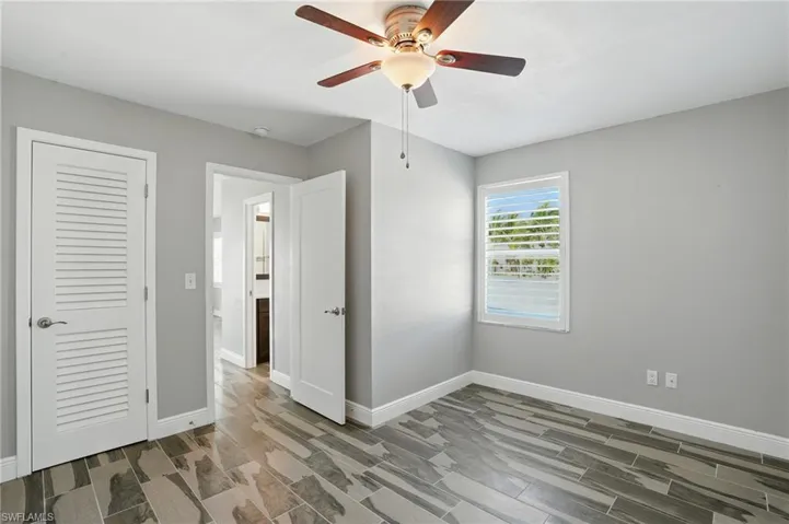 Unfurnished bedroom with wood finish floors and ceiling fan- Virtually Enhanced