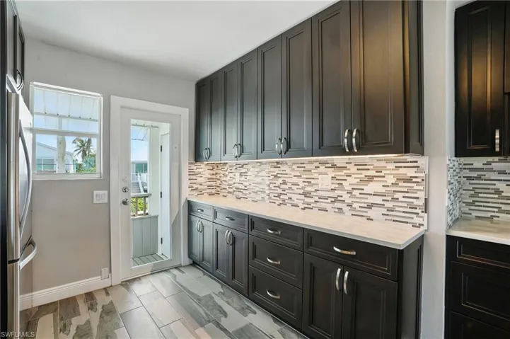 Kitchen with light countertops, backsplash, and freestanding refrigerator- Virtually Enhanced