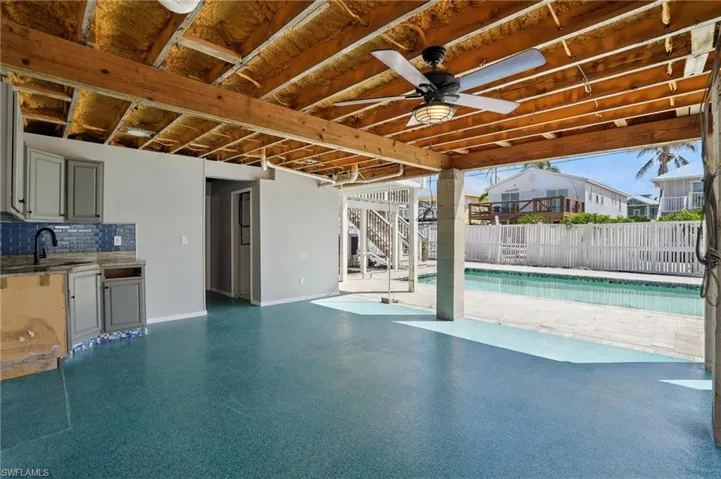 View of swimming pool with stairway, ceiling fan, a patio area, and an outdoor kitchen- Virtually Enhanced