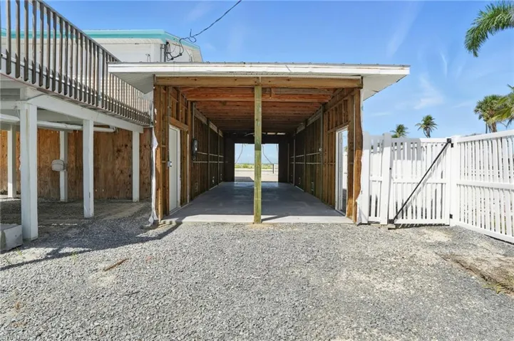 View of parking featuring an exterior structure, a carport, and gravel driveway- Virtually Enhanced