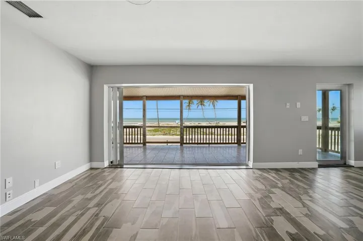 Unfurnished room with wood finished floors and baseboards- Virtually Enhanced